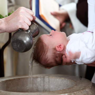 Taufe eines Babys mit Wasser über dem Taufbecken